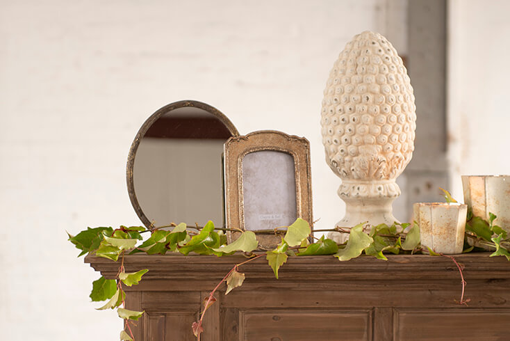 A mantelpiece with a table mirror, a photo frame, and a desk lamp