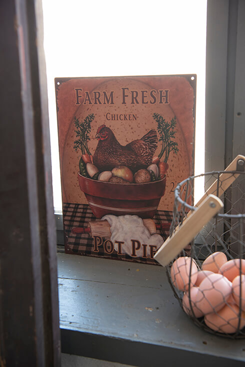 Un cestino con uova e sullo sfondo un cartello con scritto di un pollo