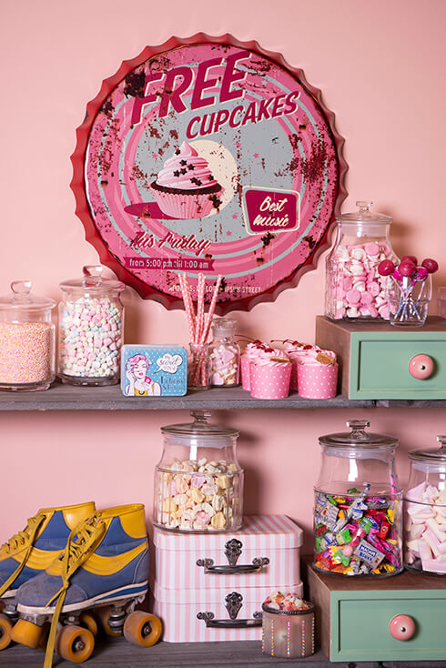 Giocattoli per bambini, barattoli di vetro con caramelle, con sullo sfondo un cartello con scritto su cupcakes