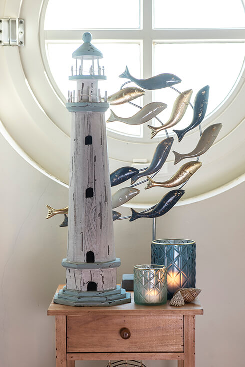 Un petit meuble avec des bougies dessus et une figurine d'un phare et de poissons
