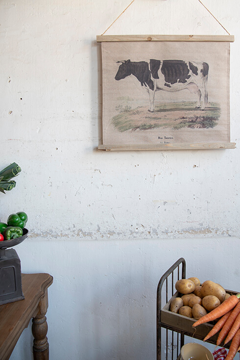 Un bol de carottes et de pommes de terre avec en arrière-plan une tenture murale d'une vache