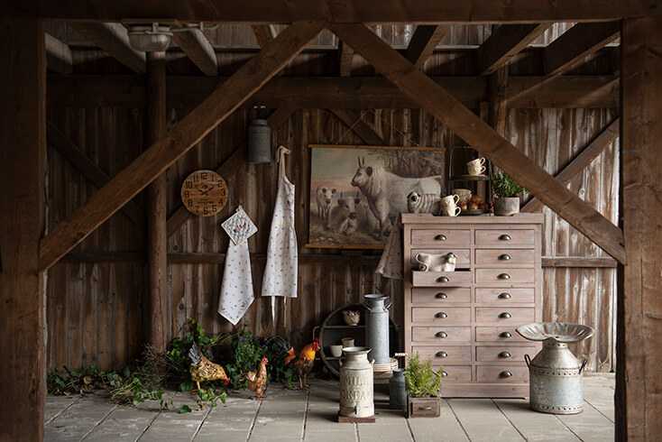 A shed with a clock, aprons, a cabinet, and a wall tapestry of animals
