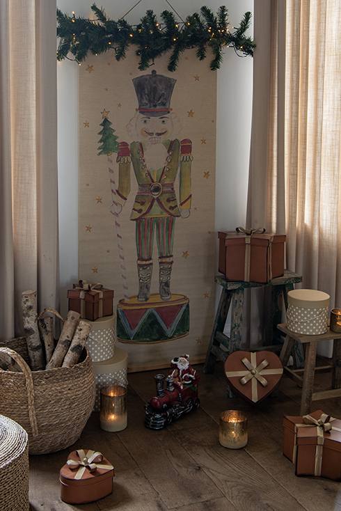 Stools with boxes, a basket with wood, and in the background a wall tapestry of a nutcracker