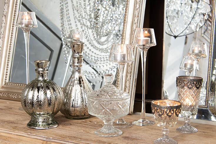 Klassieke interieurstijl met glazen waxinelichthouders, een glazen potje en twee zilverkleurige flessen