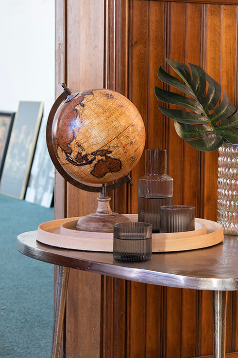 Un plateau avec un globe terrestre, une carafe et un verre sur une table d'appoint